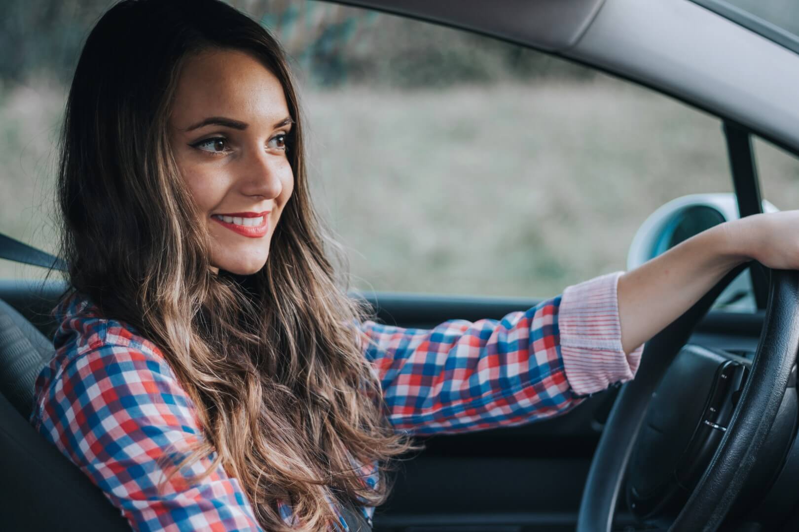 Jeune femme souriante au volant d'une voiture